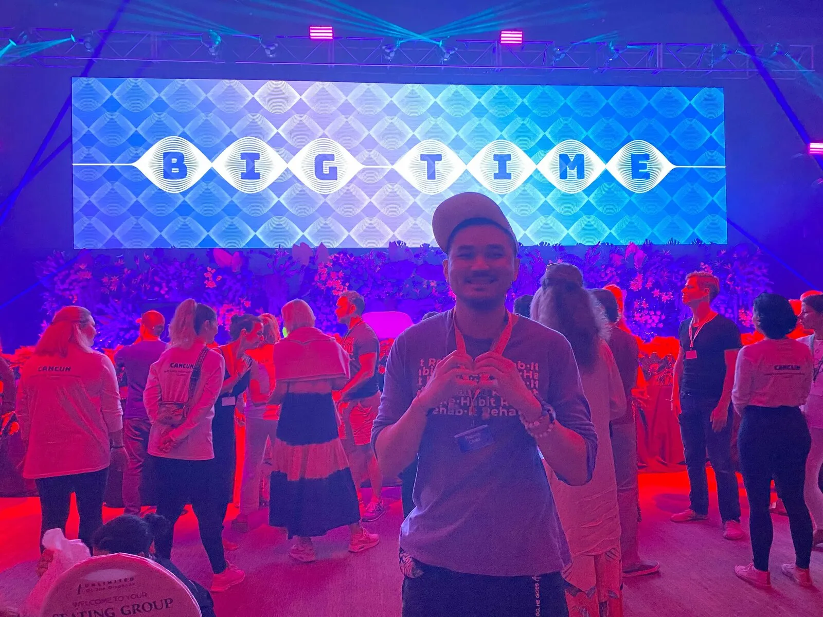 Patrick Chan in the crowd at a retreat, in front of a brightly lit stage